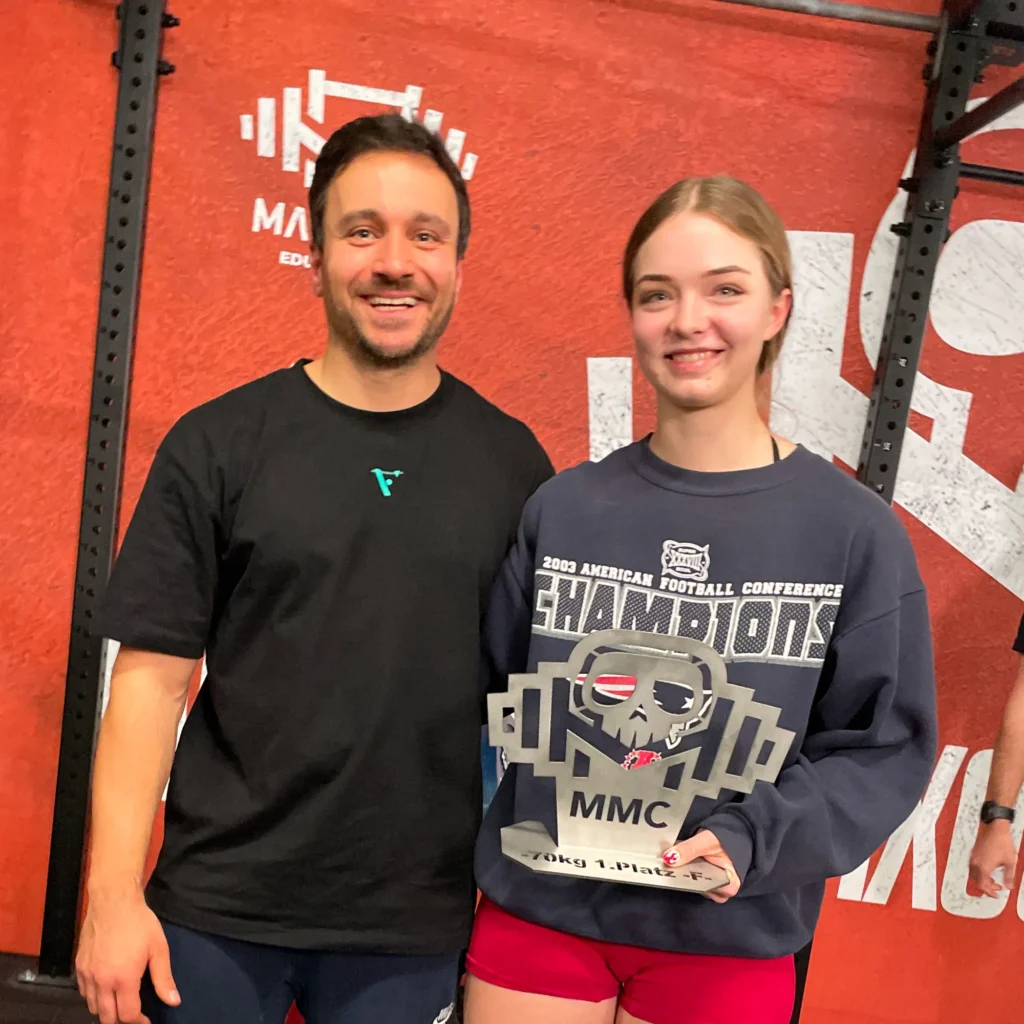 Coach Volker mit Athletin und Pokal nach Wettkampf